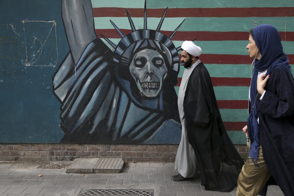 A cleric and a woman walk past an anti-U.S. mural painted on the wall of the former U.S. Embassy in Tehran.