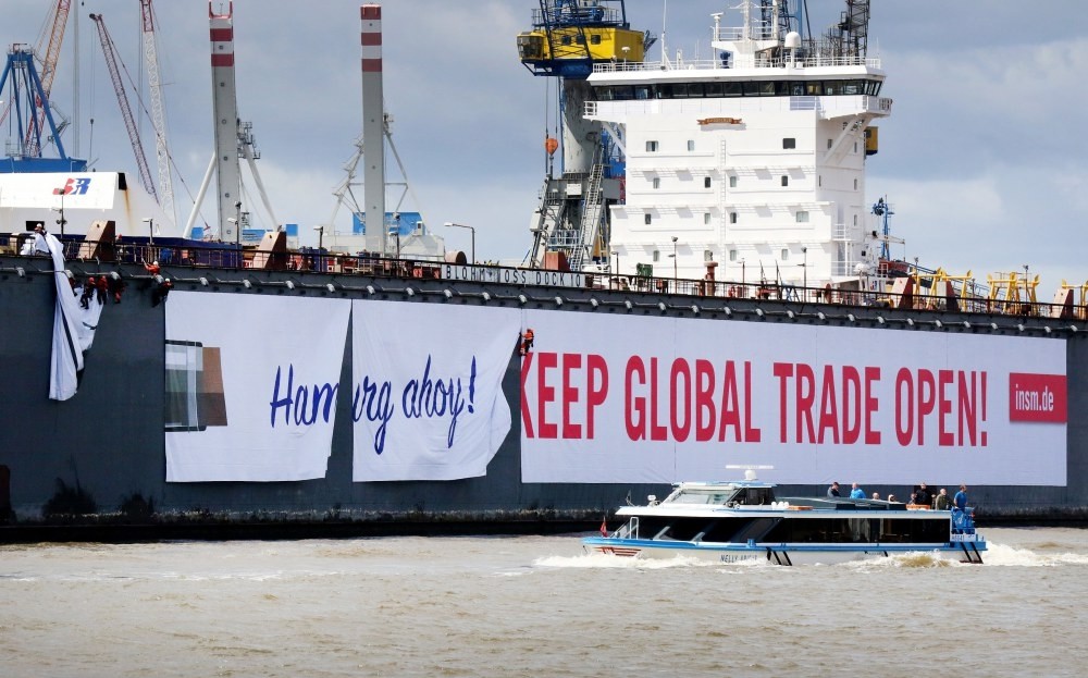 Workers hang a banner reading u2018Hamburg Ahoy! Keep Global Trade Open!, for the lobbyist organisation Initiative Neue Marktwirtschaft (INSM) on the side of a floating dock at the Blohm and Voss shipyards in preparation for the upcoming G20 Summit.