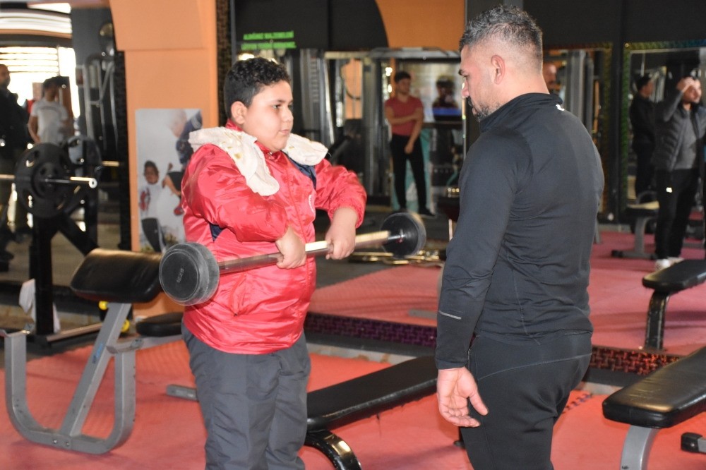 Muhammad (L) works out with an instructor at the gym.