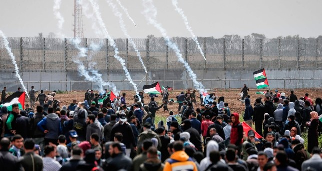 Tear gas canisters fall among Palestinian protesters during a demonstration near the border with Israel in Malaka east of Gaza City on March 30, 2019. (AFP Photo)