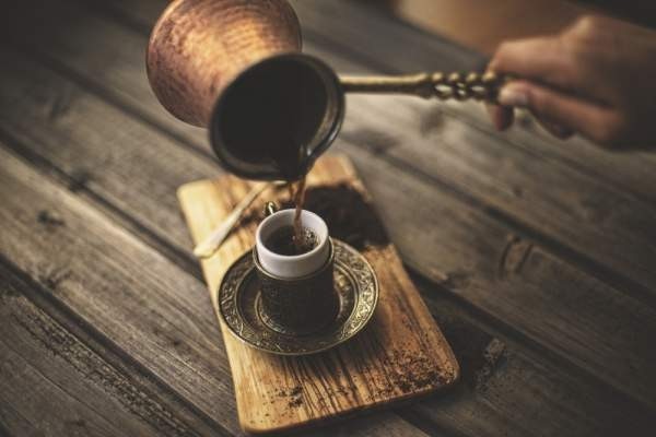 A coffee maker pours Turkish coffee into a traditional cup from a copper coffee pot. (iStock Photo)