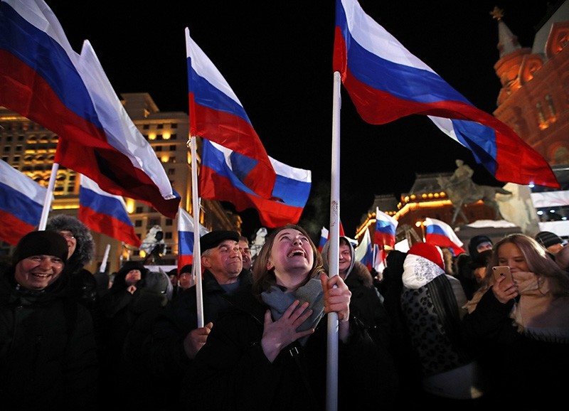 People wave Russian flags as they wait for election results in Manezhnaya square, near Kremlin in Moscow, Sunday, March 18, 2018. (AP Photo)