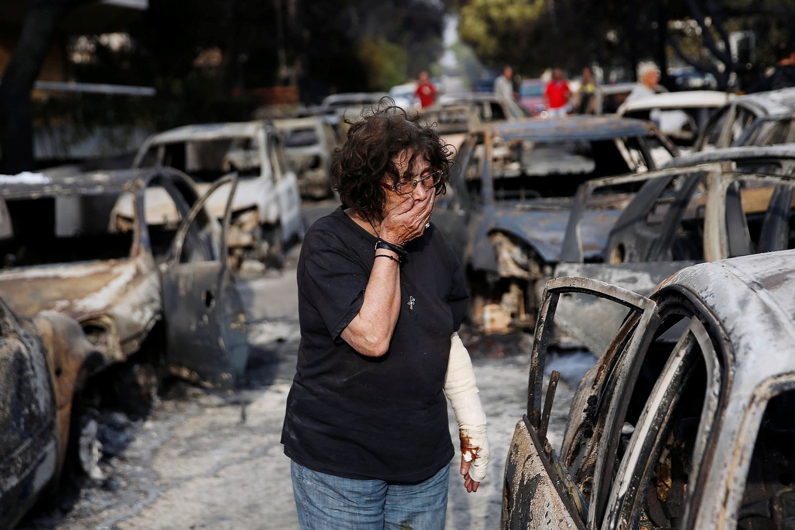 A woman reacts as she tries to find her dog, following a wildfire at the village of Mati, near Athens, Greece July 24, 2018.