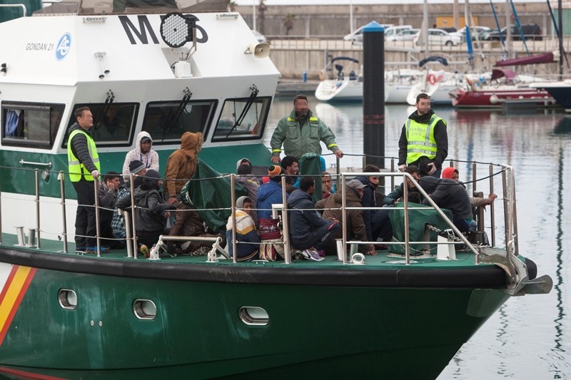 Several Civil Guard officers (L,C and R) escort migrants on board of a Spanish Sea Rescue Unit's boat upon their arrival in the port in Barbate, southern Spain (EPA Photo)