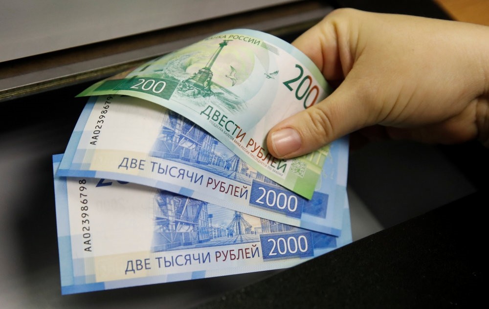 A woman holds new 200 and 2,000 ruble banknotes in a bank in Moscow.