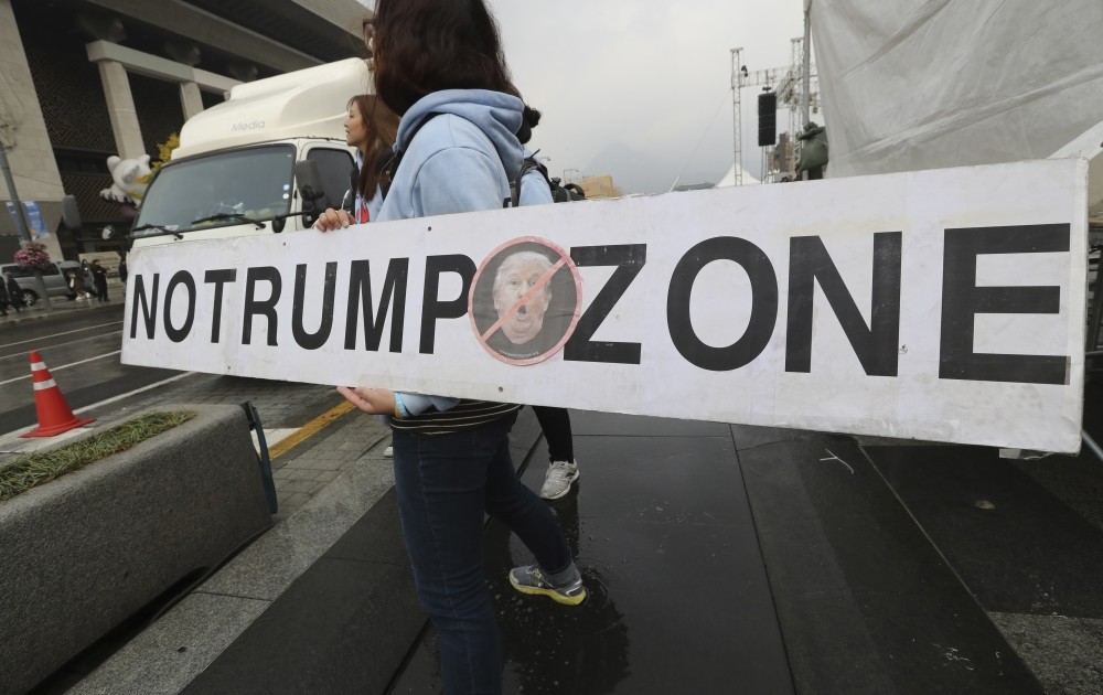 A woman holds a banner opposing President Trump's planned visit to the country near the U.S. Embassy in Seoul, South Korea, Nov. 3. 