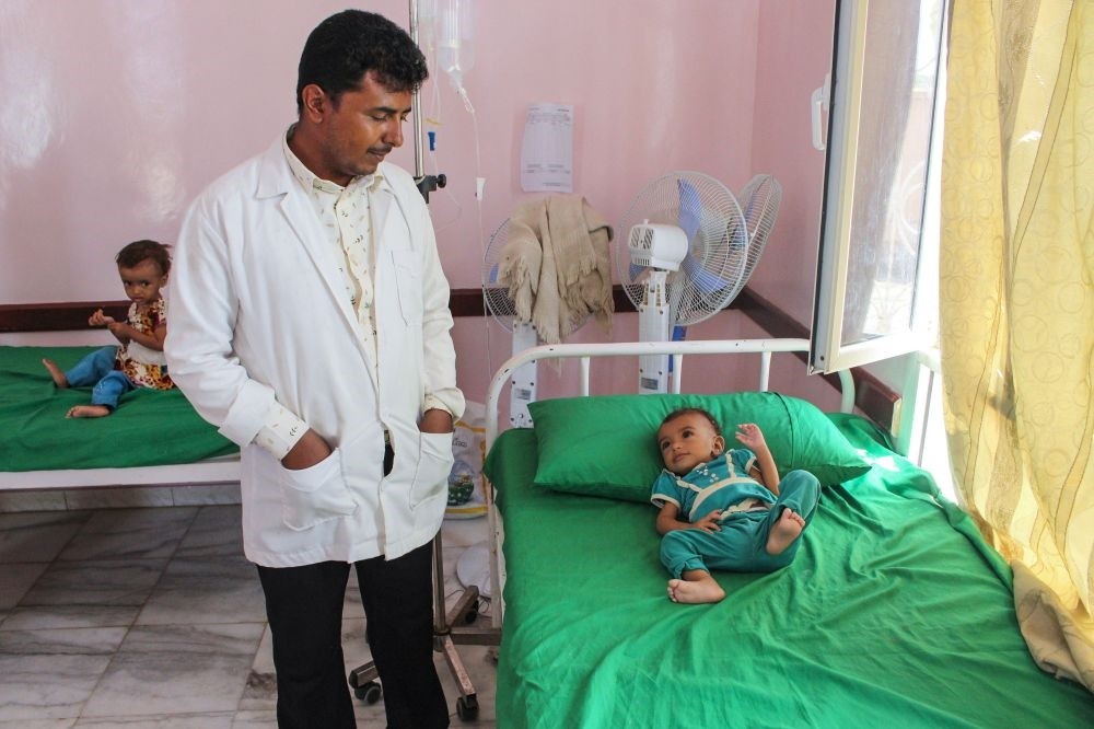 A hospital staffer looks at a Yemeni child suffering from malnutrition lying on a bed at a hospital in the northern district of Abs in the northwestern Hajjah province,  Sept. 19.