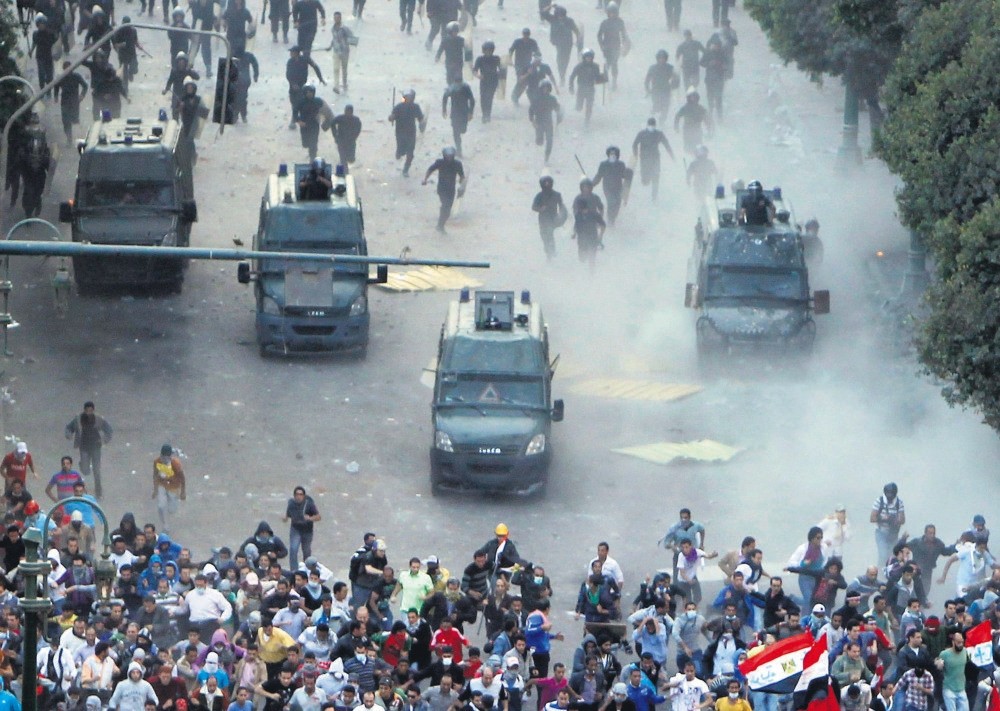 Protesters run from riot police during a demonstration against the junta regime in their country, at Tahrir square, Cairo, Nov. 23, 2012.