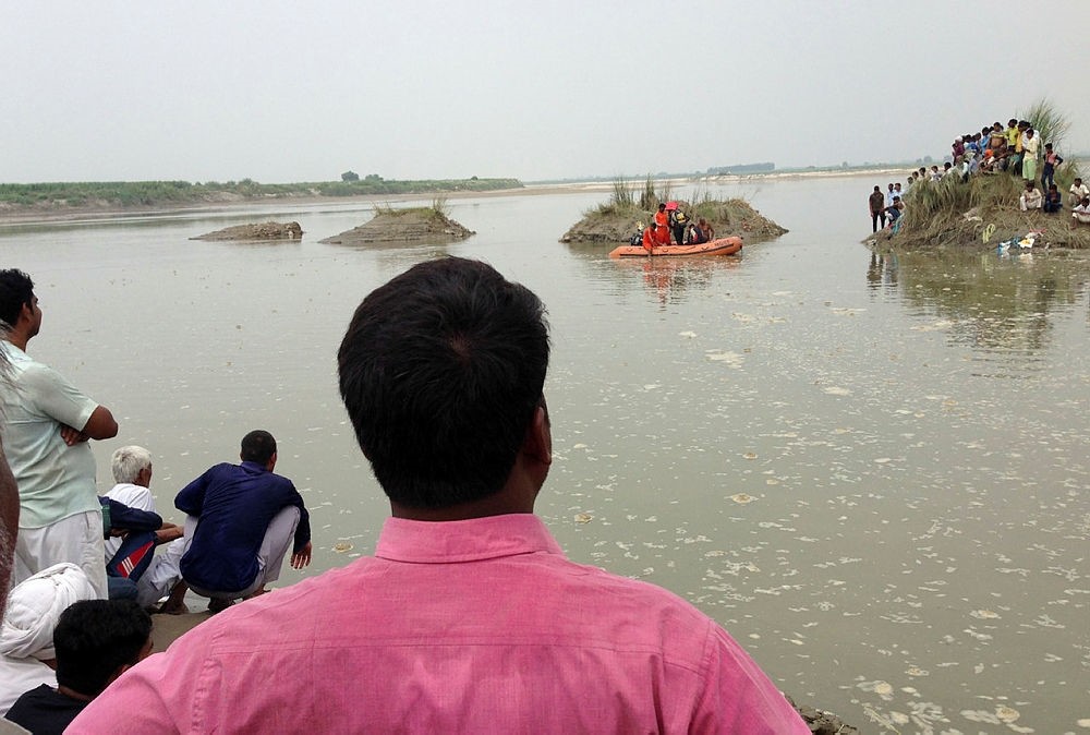 Villagers gather at the spot of a boat capsize as rescuers search in the Yamuna River near Baghpat town in Uttar Pradesh state, India, Thursday, Sept.14, 2017. (AP Photo)