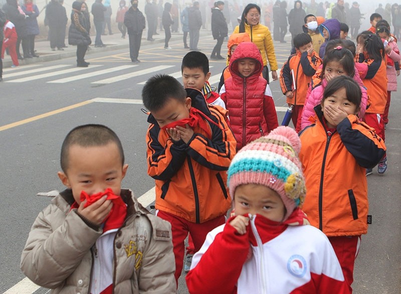 This photo taken Dec. 23, 2015, shows elementary school students covering their mouths and noses after the classes were suspended because of ,red alert, for heavy smog in Binzhou, east China's Shandong province. (AFP Photo)