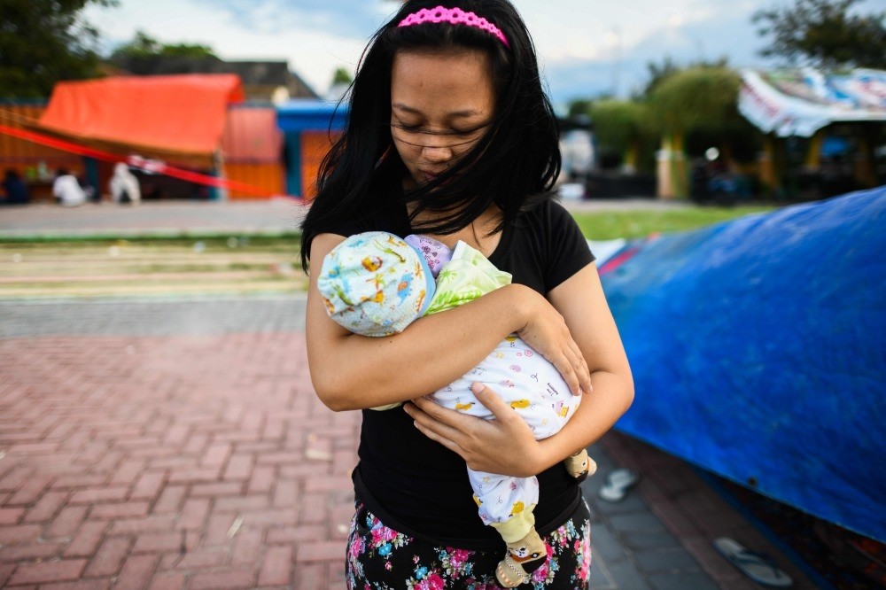 A quake survivor cradles her 2-month-old son at a makeshift camp, Palu, Oct. 2.