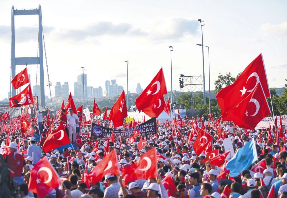 People wave Turkish national flags as they stand near the July 15 Martyrs Bridge in Istanbul on July 15, 2017. Turkey has marked almost two years since the defeat of the coup attempt.