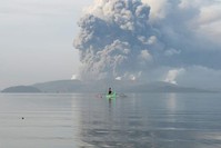  A youth living at the foot of Taal volcano rides an outrigger canoe while the volcano spews ash as seen from Tanauan town inBatangas province, Manila, Jan. 13, 2020. (AFP Photo)