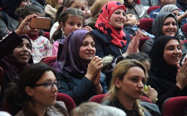 Syrian refugees sing along as the choir sings on stage.