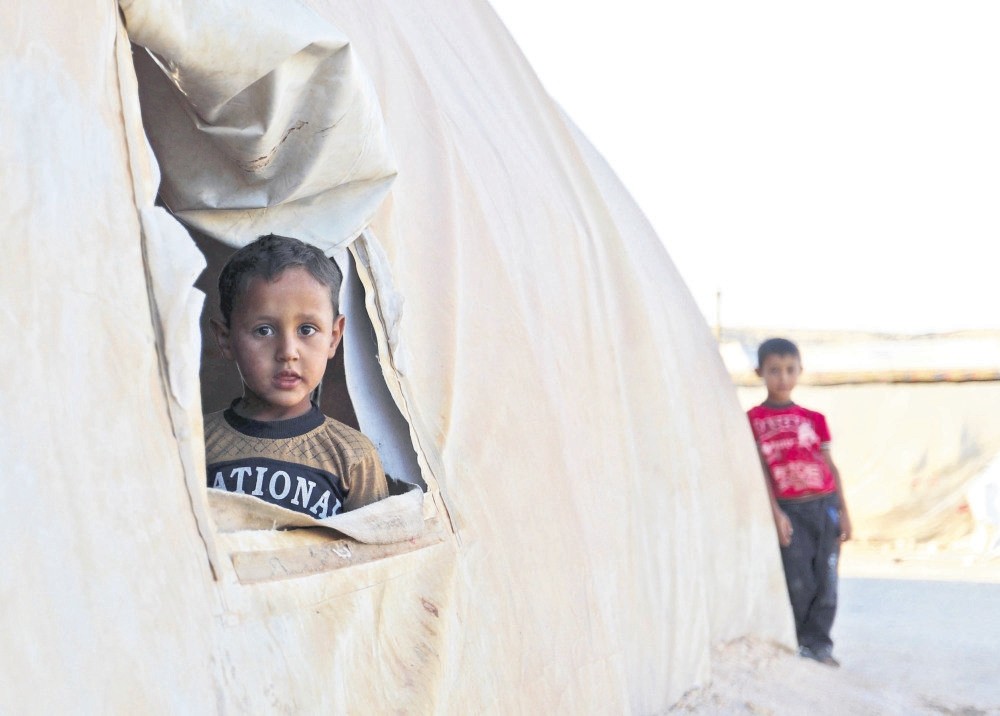 A young boy looks out from a tent in a camp for the displaced in southern Idlib, a short distance from the border with Turkey, Aug. 26.