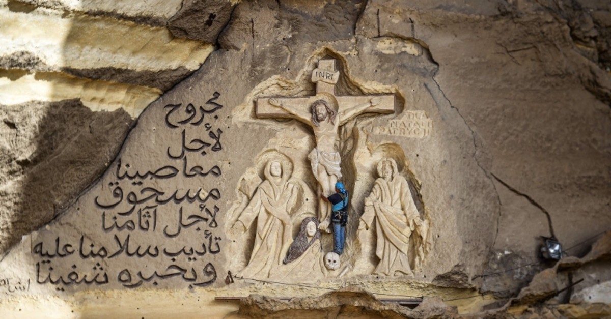 Polish artist Mario, sculptor of St. Simon the Tanner Monastery complex, works on a scene relief depicting the Crucifixion of Jesus Christ and a verse in Arabic from the Biblical Book of Isaiah (AFP Photo)