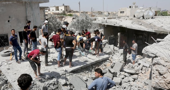 Civil society organizations and rescuers work through the rubble of collapsed buildings destroyed by Syrian regime attacks in Idlib's de-escalation zone, June 11, 2019.
