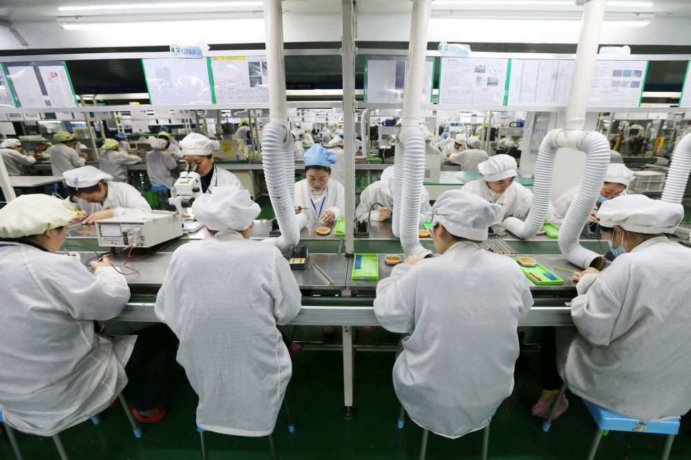 Chinese employees working on micro and special batteries for mobile phones at a factory.