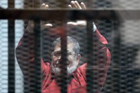 Egypt's first democratically elected President Mohammed Morsi stands behind bars, June 21, 2015. (AFP PHOTO)