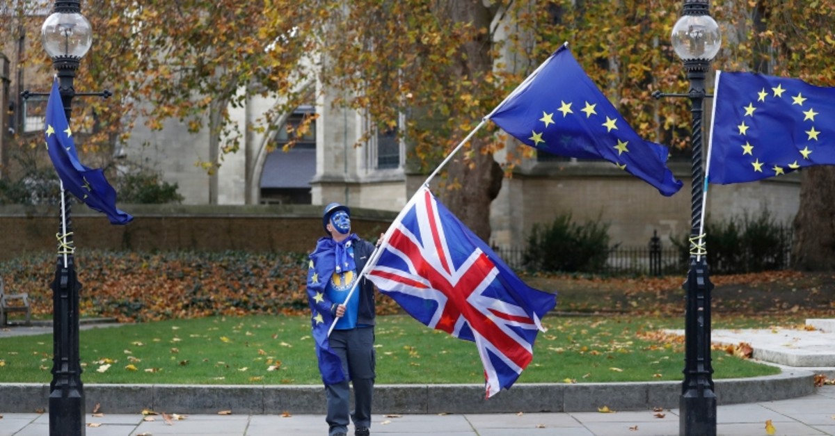 An anti Brexit, pro European Union campaigner waves flags near Parliament in London, Wednesday, Nov. 22, 2017. (AP Photo)