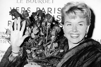 In this April 15, 1955 file photo, American actress and singer Doris Day holds a bouquet of roses at Le Bourget Airport in Paris, France after flying in from London. (AP Photo)