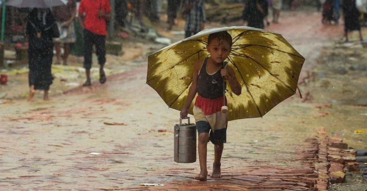 A Rohingya refugee boy shelters under an umbrella as he makes his way during a monsoon rain at the Kutupalong refugee camp, Ukhia, Sept. 12, 2019. (AFP Photo)