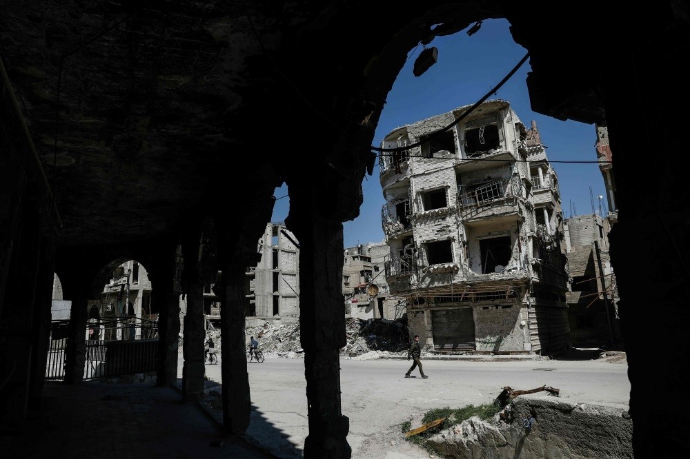 Syrians walking past damaged buildings in the moderate Syrian opposition-held town of Douma on the eastern outskirts of Damascus, April 7. ( AFP Photo)