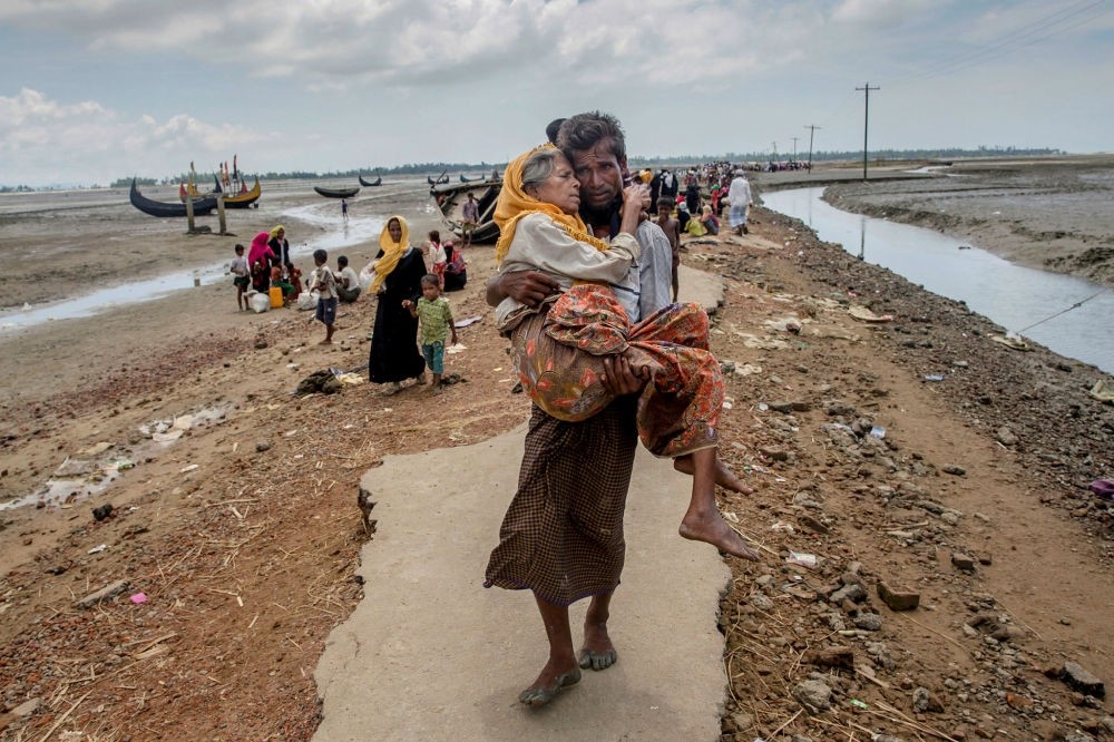 A Rohingya Muslim man walks towards a refugee camp carrying his mother after crossing over from Myanmar into Bangladesh, Sept. 16.