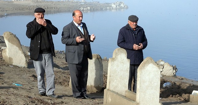 القرويون يقرؤون الفاتحة على أحد القبور التي كشف عنها انحسار مياه السد İHA