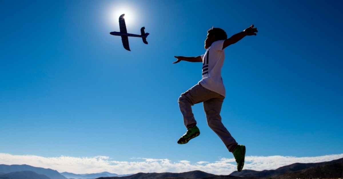 A boy plays with a toy plane on the eve of a solar eclipse, in La Higuera, Coquimbo Region, in the Atacama desert about 580 km north of Santiago, on July 1, 2019. (AFP Photo)