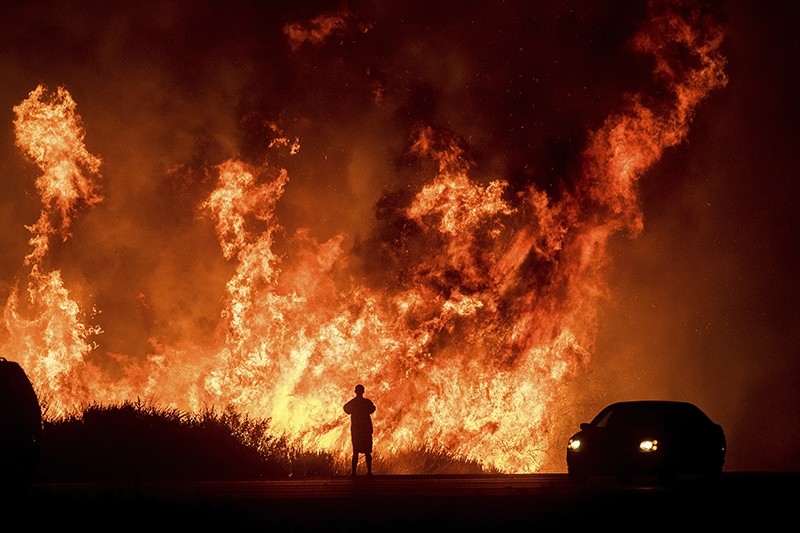 A motorists on Highway 101 watches flames from the Thomas fire leap above the roadway north of Ventura, Calif., on Dec. 6, 2017. (AP Photo)