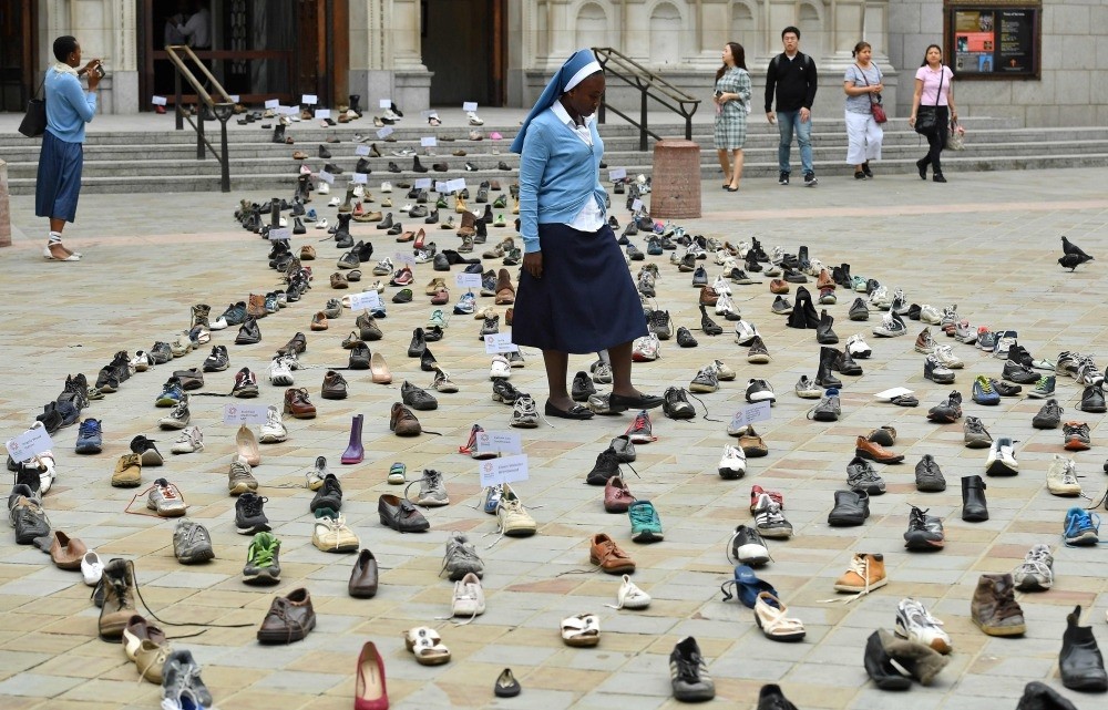 Catholic Agency For Overseas Development's (CAFOD) Sister Clara from Zambia, walks through shoes displayed outside Westminster Cathedral, London, Aug. 15.