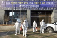 In this Wednesday, Feb. 19, 2020, photo, workers wearing protective gears spray disinfectant against the coronavirus in front of a church in Daegu, South Korea. (Newsis via AP)