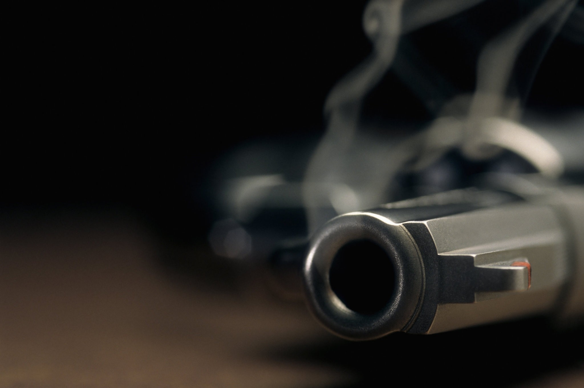 A gritty crime scene image of a smoking hand gun, revolver, lying on the floor with narrow focus on the tip of the barrel and dark background. (FILE Photo)