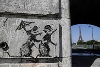 A recent artwork by street artist Banksy is pictured in Paris near the Eiffel Tower.