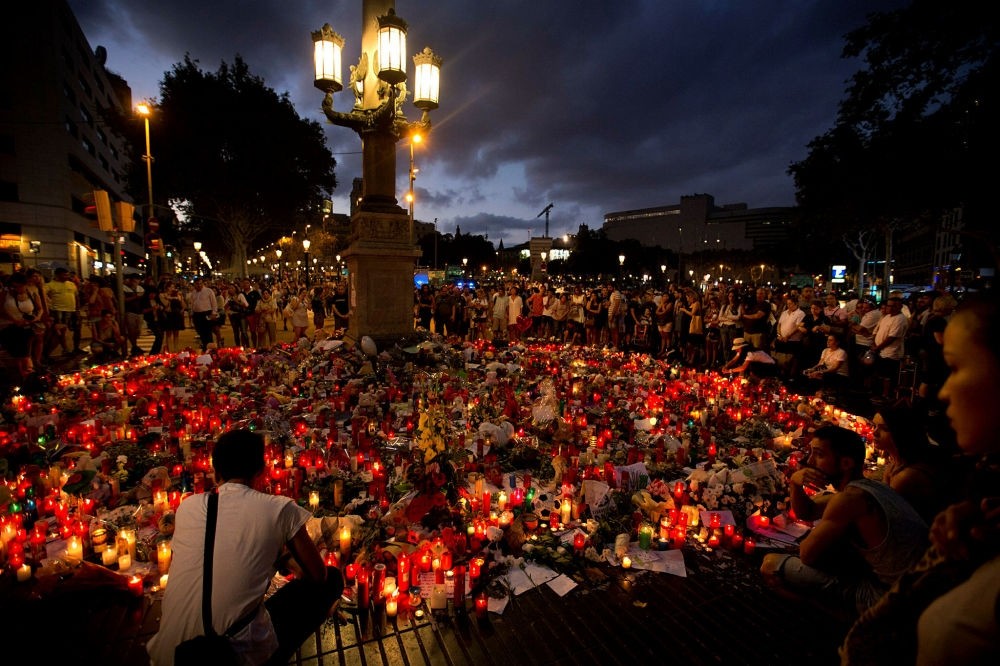 People stand next to candles and flowers placed on the ground, after the terror attack that killed  at least 14 people and wounded over 120 in Barcelona, August 20