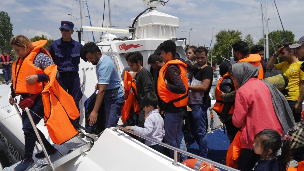 Soldiers accompany intercepted immigrants to shore.