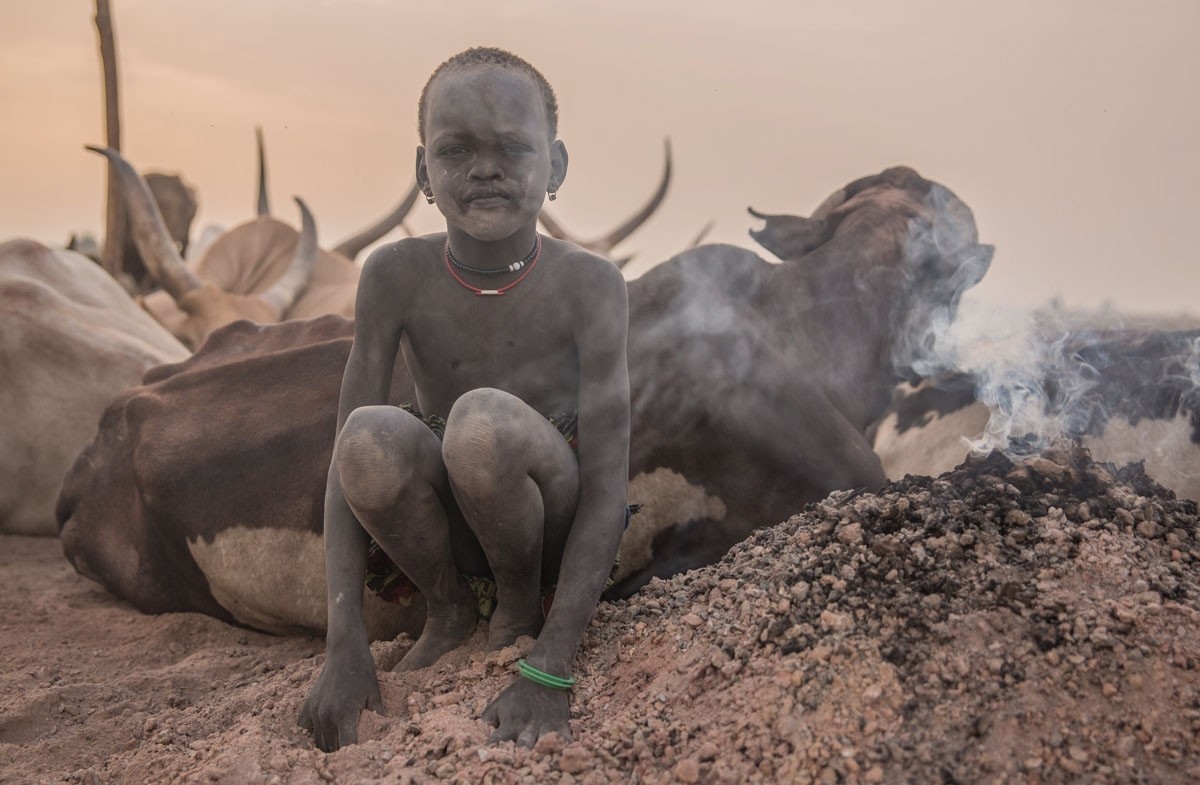 A boy uses white ash from burned cow dung as a mosquito repellent. 