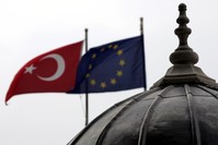 The Turkish and European Union flags waving side by side in Istanbul, where the minarets and domes of mosques and churches dominate the cityu2019s silhouette.