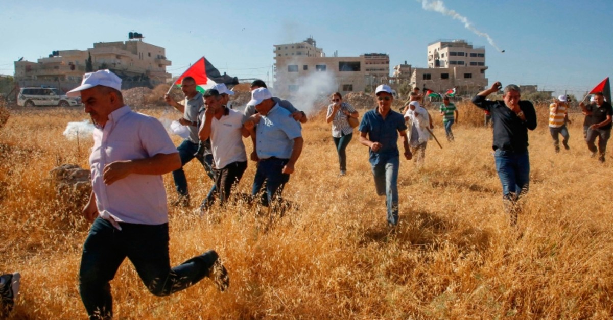 Palestinians run for cover after Israeli forces fire tear gas canisters during a demonstration against the demolishing of buildings in the Palestinian village of Beit Sahur in the occupied West Bank, July 20, 2019. (AFP Photo)