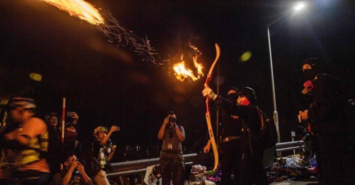 A protester releases a fire arrow with his bow during a clash with police at the Chinese University in Hong Kong, Tuesday, Nov. 12, 2019. (AFP Photo)