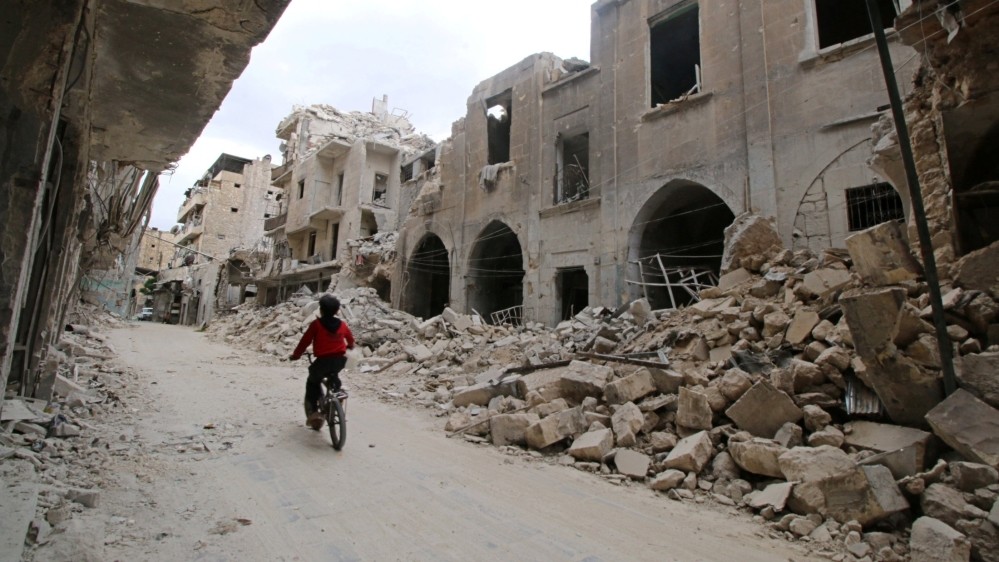 A boy rides his bicycle amid ruins in war-torn Aleppo (Reuters Photo)