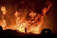 A motorists on Highway 101 watches flames from the Thomas fire leap above the roadway north of Ventura, Calif., on Dec. 6, 2017. (AP Photo)