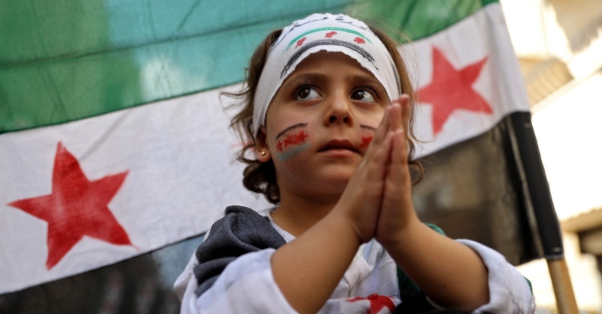 A Syrian girl claps as she takes part in a protest against the regime in the town of Kafr Takharim Syria's northwestern Idlib governorate on Sept. 27, 2019. (AP Photo)