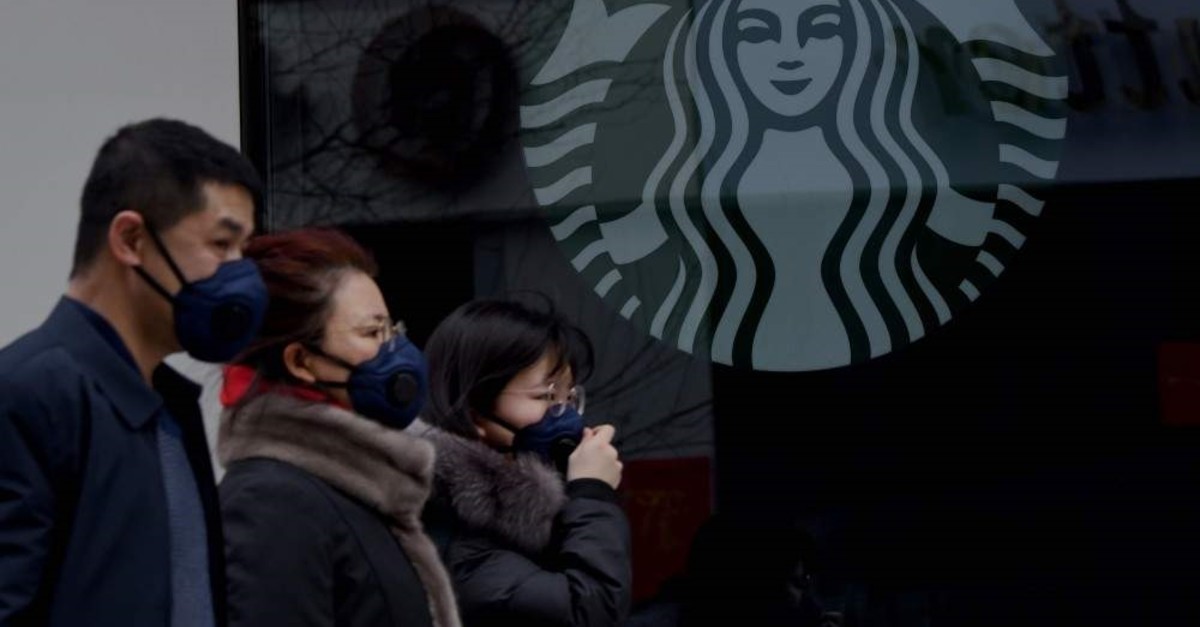 People wearing protective face masks walk past a closed Starbucks coffee shop at a grocery store in Beijing, Jan. 29, 2020. (AFP Photo)