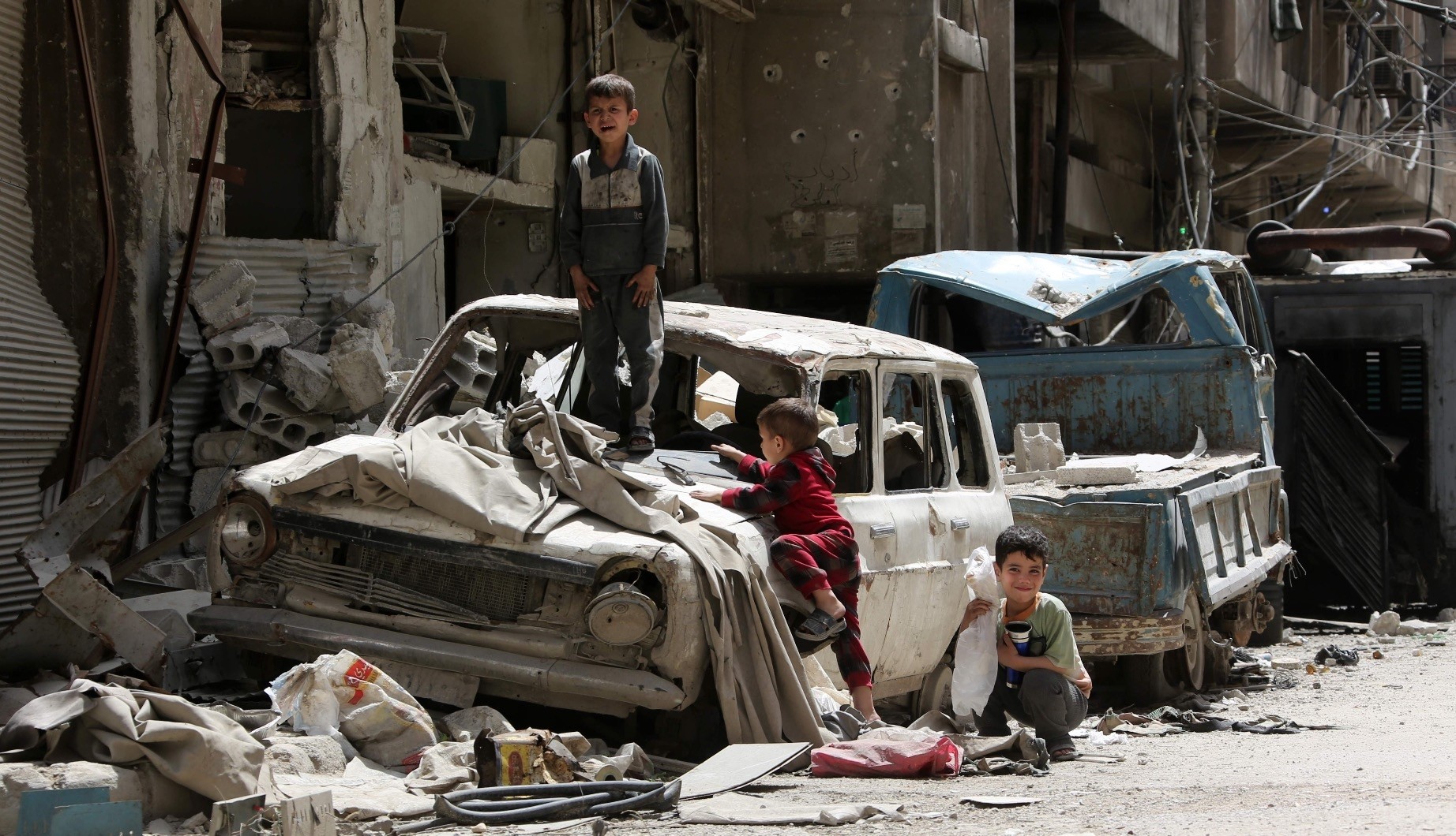 Syrian boys play on a destroyed car, Douma, on the outskirts of Damascus, April 19.