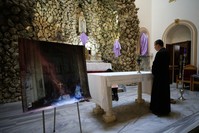 Father Gabriel Ferone stands next to a photo of Notre Dame Cathedral inside the church.