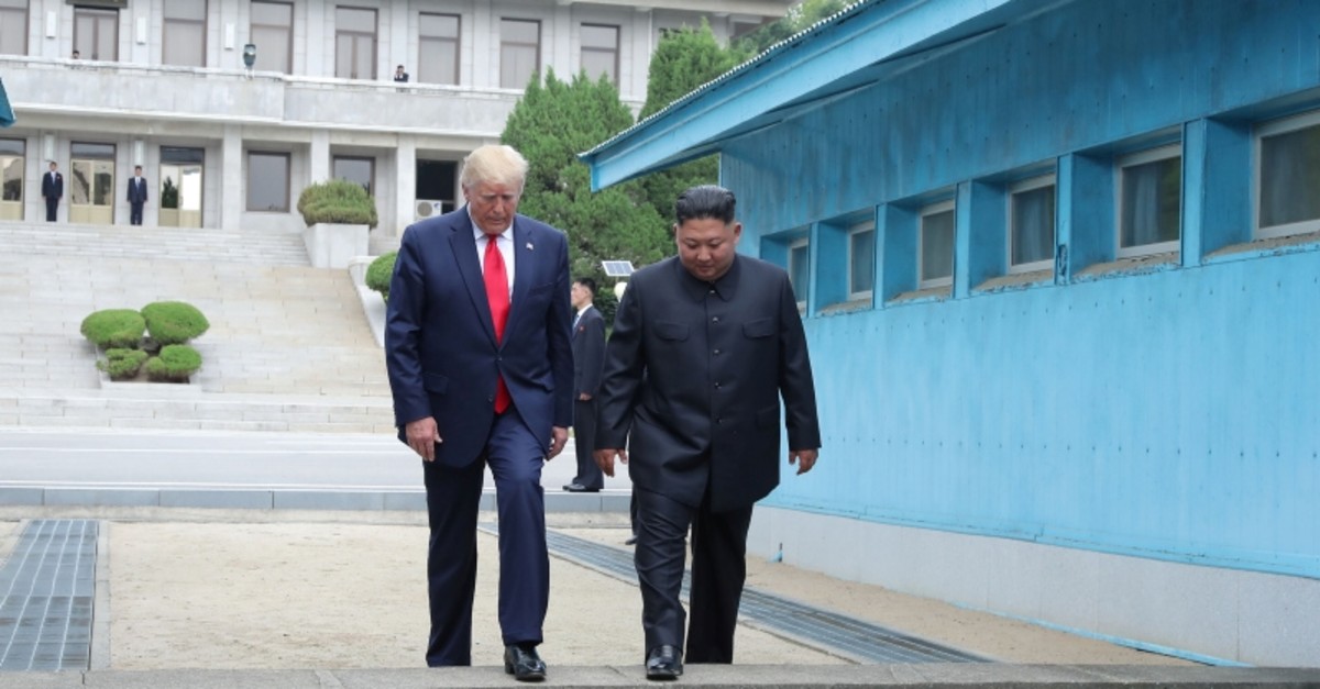 U.S. President Donald Trump and North Korean leader Kim Jong Un cross over a military demarcation line at the demilitarized zone (DMZ) separating the two Koreas, in Panmunjom, South Korea, June 30, 2019. (KCNA via Reuters)