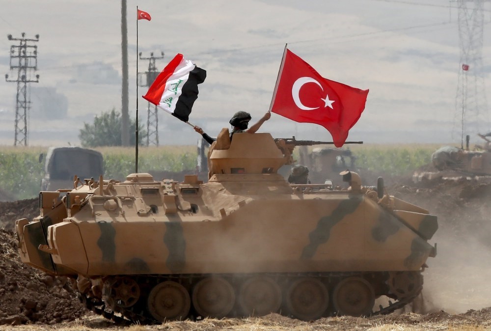 Soldiers hold Turkish (R) and Iraqi (L) national flags while standing in the turret of a Turkish armored vehicle during in a military exercise near the Turkish-Iraqi border in Silopi district, in u015eu0131rnak city, Sept. 26.