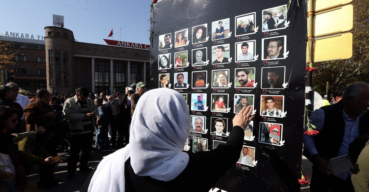 A woman touches the photos of victims during a commemoration ceremony at the scene of attacks, Oct. 10, 2019.